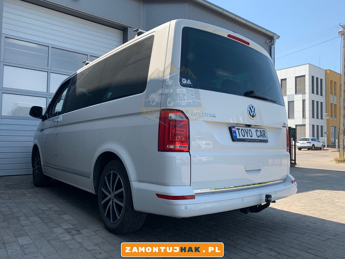 321651600001 zdjecie haka zamontowanego w vw t6 na zdjeciu bialy multivan z hakiem holowniczym zdjecie od tylu dobrze widoczny hak i jak wychodzi po montazu 